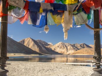 blue yellow and red textile on gray sand near lake and mountain during daytime